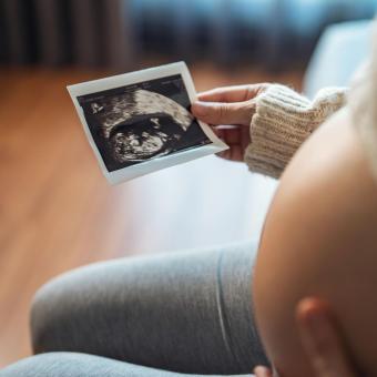 Pregnant woman looking at her ultrasound report.