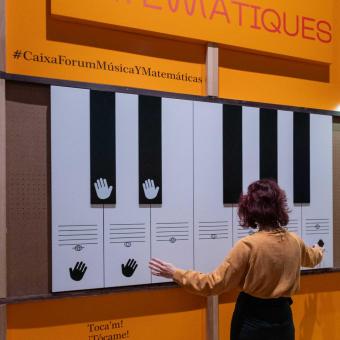 Una visitant interactúa amb el teclat d'entrada de l'exposició «Música i matemàtiques». 