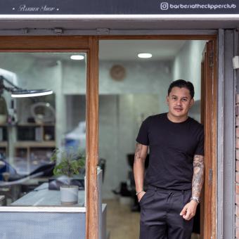 Juan Gabriel Agudelo en la entrada de su barbería, The Clipper Club, en Barcelona. 