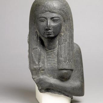 Representation of a woman holding a sistrum decorated with the face of Hathor, About 1292–1189 BC, Basalt, Egypt. 1853,0822.3 © The Trustees of the British Museum (2023).