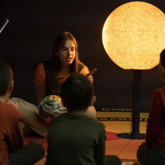 Una educadora y unos pequeños visitantes, en el Planetario Burbuja de CosmoCaixa.