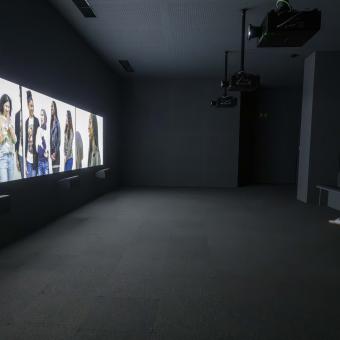 Visitante delante de la videoinstalación de tres canales de la exposición «Fuera de marco. Obras de Rineke Dijkstra y Philippe Parreno».