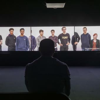 Visitante delante de la videoinstalación de tres canales de la exposición «Fuera de marco. Obras de Rineke Dijkstra y Philippe Parreno».