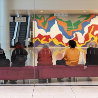 Interior del vestíbulo de CaixaForum Barcelona con visitantes. Al fondo, el mural Splat de Sol Lewitt.