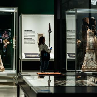 Una mujer admirando los diversos vestidos nupciales de la exposición «Voces del Pacífico», en CaixaForum Madrid.