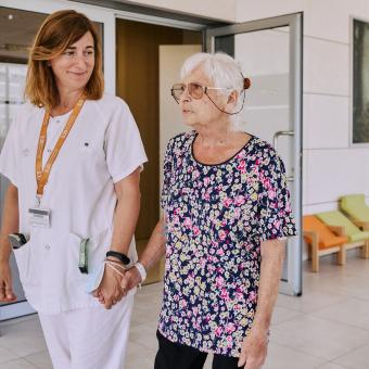 Una professional sanitària acompanyant una persona gran beneficiària dels programes socials de la Fundació ”la Caixa”.