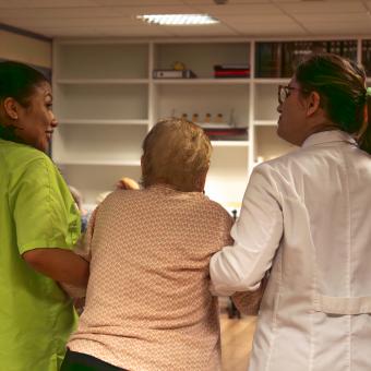Dues treballadores de la unitat de cures pal·liatives San Camilo de Tres Cantos (Madrid) ajudant una pacient.