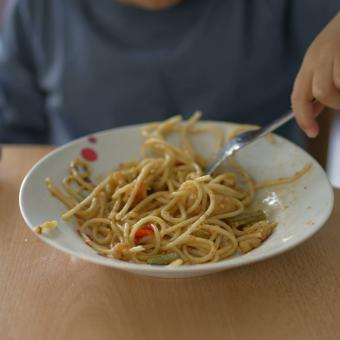 A boy eating a plate of pasta.