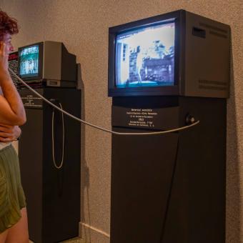 Visitant interactuant amb vídeos de cinema doméstico a l'exposició «[Rec]ords. La vida a través del cinema domèstic» a CaixaForum València.