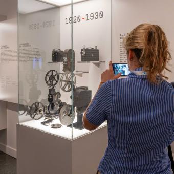 Visitant prenent fotos de càmeres antigues a la exposició «[Rec]ords. La vida a través del cinema domèstic» a CaixaForum València.