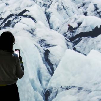 Una visitant fotografia l'exposició, que conté imatges evocadores.