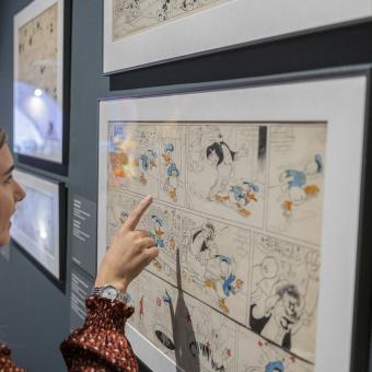 Una dona admirant una de les obres de la mostra «Còmic. Somnis i història» a CaixaForum Girona.