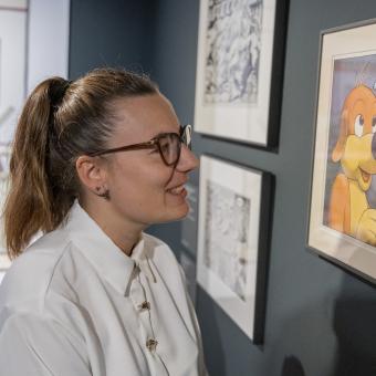 Una visitant somriu observant una de les vinyetes exposades a CaixaForum Girona.