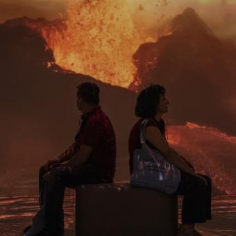 Dues persones veient imatges d'un volcà en plena explosió.