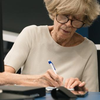 Una señora tomando apuntes en los talleres Competencias Digitales +60.