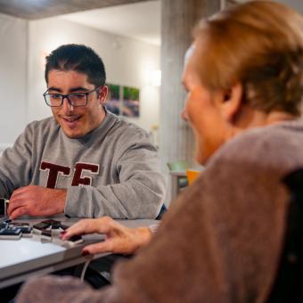 El voluntario Adrián Casado juega al dominó con Luisa.