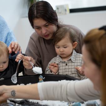Algunes mares usuàries de CaixaProinfància donant menjar als seus fills.