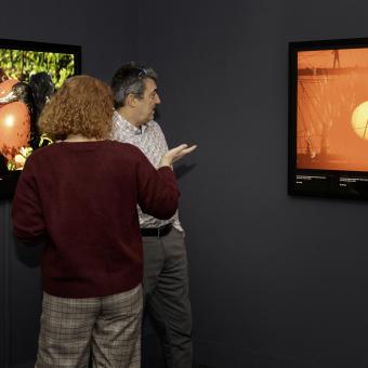 Dos visitantes observan una imagen de una puesta de Sol en Australia.