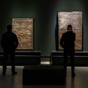 Dos visitantes admirando las obras expuestas en la exposición «Asurbanipal» en CaixaForum Madrid. 