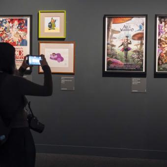 Una visitante haciendo fotos a algunas de las obras presentes en la exposición «Los mundos de Alicia» en CaixaForum València. 
