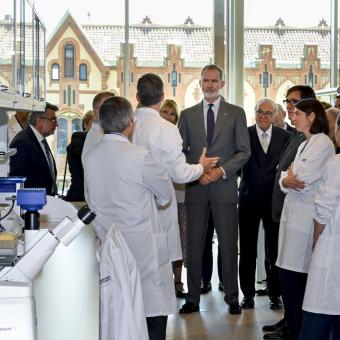 S. M. el Rey, Isidro Fainé y Salvador Illa escuchando a los investigadores del CaixaResearch Institute.