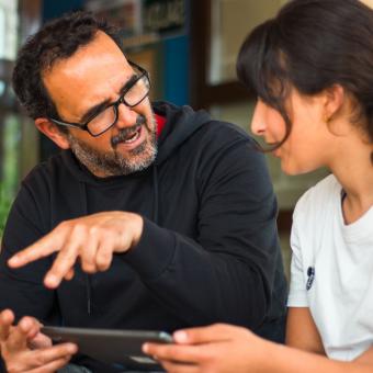 El director del CEIP Ramón y Cajal de Alpartir hablando con una alumna del centro. 