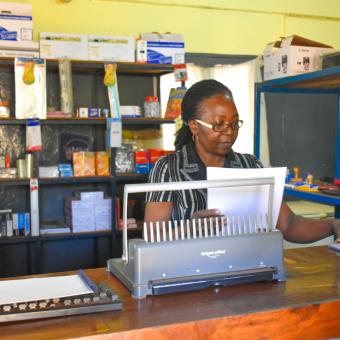 Crisália Nhambi working in her stationery shop.