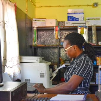 Crisália Nhambi working in her stationery shop.