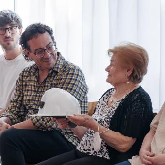 Un asistente hablando con una señora durante el encuentro intergeneracional en el Centro Social para Personas Mayores El Llano, en Gijón.  