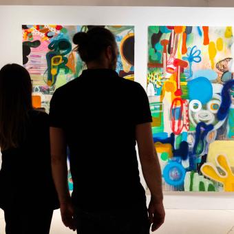 dos personas observando algunas de las obras expuestas en la muestra «Rumores infundados. Javier y Rafa Forteza» en CaixaForum Madrid.