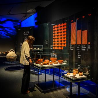 Una mujer observando algunas de las piezas presentes en la exposición «Naufragios. Arqueología sumergida» en CaixaForum Zaragoza..