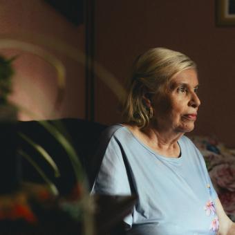 Una dona gran asseguda sola a casa seva.