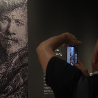 Un hombre fotografiando una de las obras de la exposición «Rembrandt. Un mundo en grabados», en CaixaForum València.