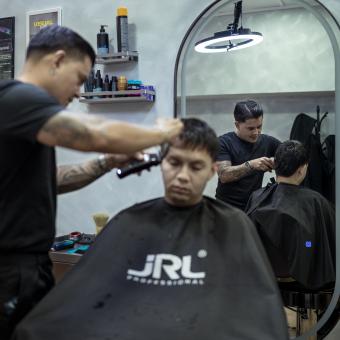 Juan cortándole el pelo a un cliente. 