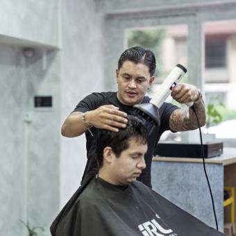 Juan secándole el pelo a un cliente. 