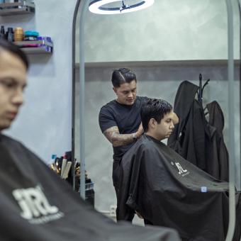 Juan le corta el pelo a un cliente. 