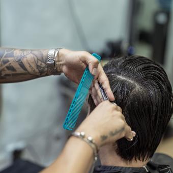 Juan cortándole el pelo a un cliente. 