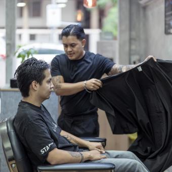 Juan preparando a uno de sus clientes para cortarle el pelo. 