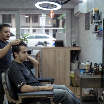 Juan asesora a su cliente y le ayuda a decidir qué corte de pelo hacerse. 