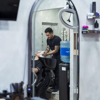Juan le lava el pelo a su cliente antes de empezar con el corte. 