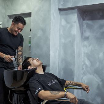 Juan le lava el pelo a su cliente antes de empezar con el corte. 