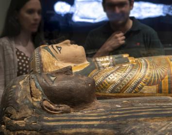 Visitantes observan una de las piezas expuestas en Momias de Egipto, una de las muestras más concurridas en CaixaForum Sevilla.
