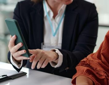 Una dona assessora una altra sobre drets digitals usant un smartphone.