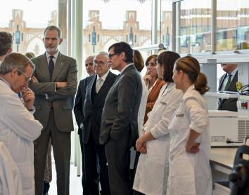 S. M. el Rei, Isidre Fainé i Salvador Illa escoltant els investigadors del CaixaResearch Institute.