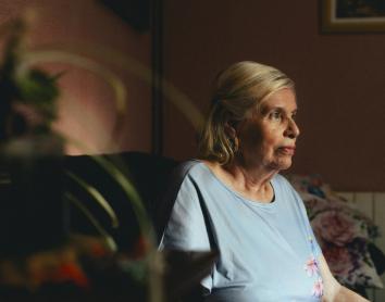 Una dona gran asseguda sola a casa seva.