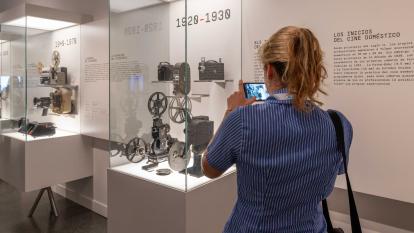 Visitant prenent fotos de càmeres antigues a la exposició «[Rec]ords. La vida a través del cinema domèstic» a CaixaForum València.