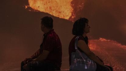 Dues persones veient imatges d'un volcà en plena explosió.