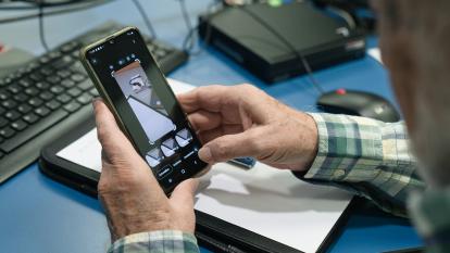 Una persona mayor aprendiendo a editar fotografías con su smartphone.