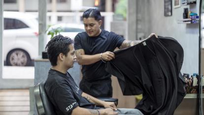Juan preparando a uno de sus clientes para cortarle el pelo.