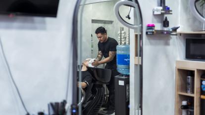 Juan le lava el pelo a su cliente antes de empezar con el corte.